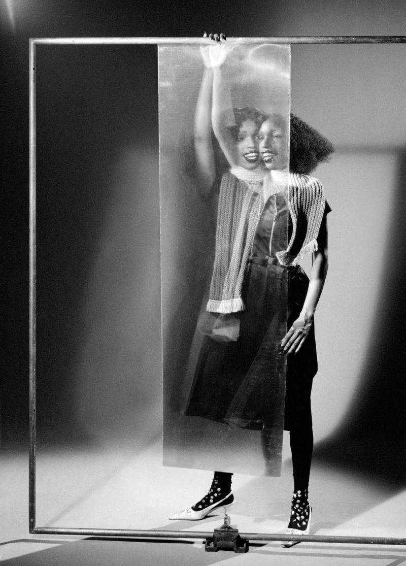 Black and white portrait of John Glacier holding a translucent panel inside a metal frame studio setup