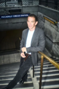 Man leaning against a handrail on the stairs outside Piccadilly Circus station in an editorial portrait.