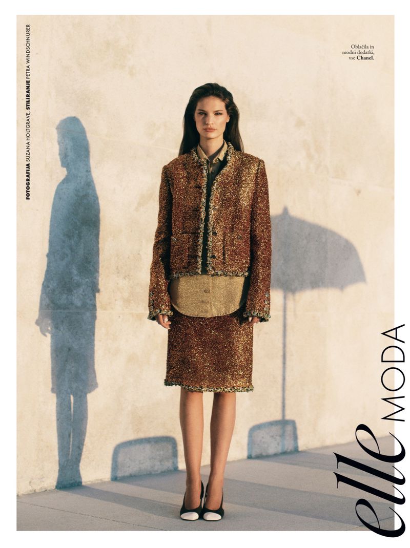 Model Faretta wearing a textured tweed jacket and skirt ensemble standing outdoors in warm sunlight for Elle Slovenia