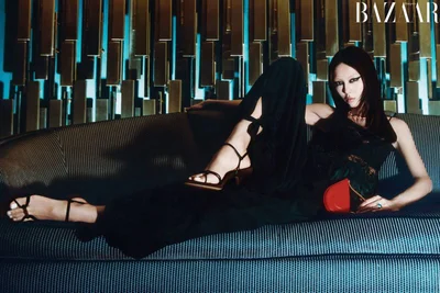 Model reclining on a striped sofa against a textured metal wall for Harper's Bazaar China editorial
