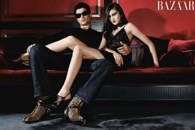 Two models posing on a red sofa for Harper's Bazaar China editorial photographed by Haiyang York