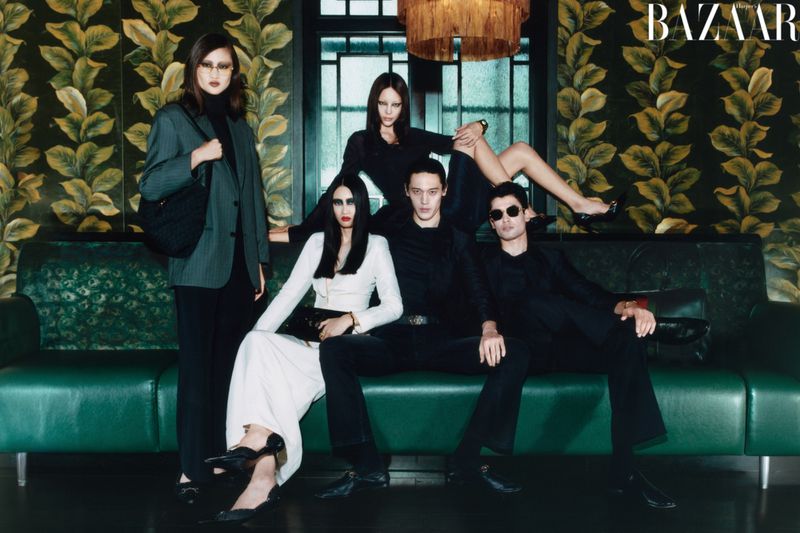 Group of models in styled attire posing on a green leather couch before patterned botanical wallpaper for Harper's Bazaar China.