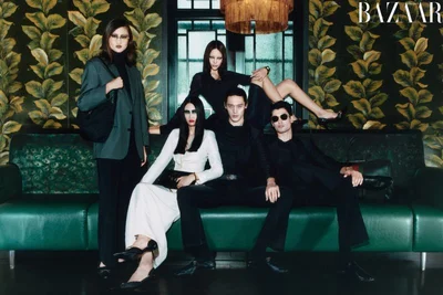 Group of models in styled attire posing on a green leather couch before patterned botanical wallpaper for Harper's Bazaar China.