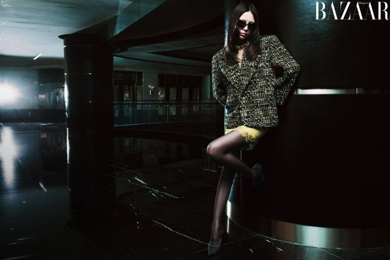 Model leaning against a dark column in a tweed jacket and sunglasses for Harper's Bazaar China