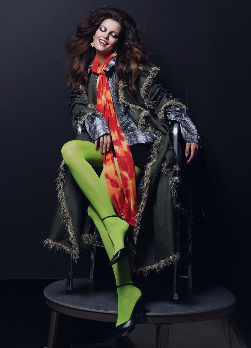Model Vanessa Fuchs seated in a green fringe coat and lime tights for Numero Switzerland, photographed by Fadil Berisha.