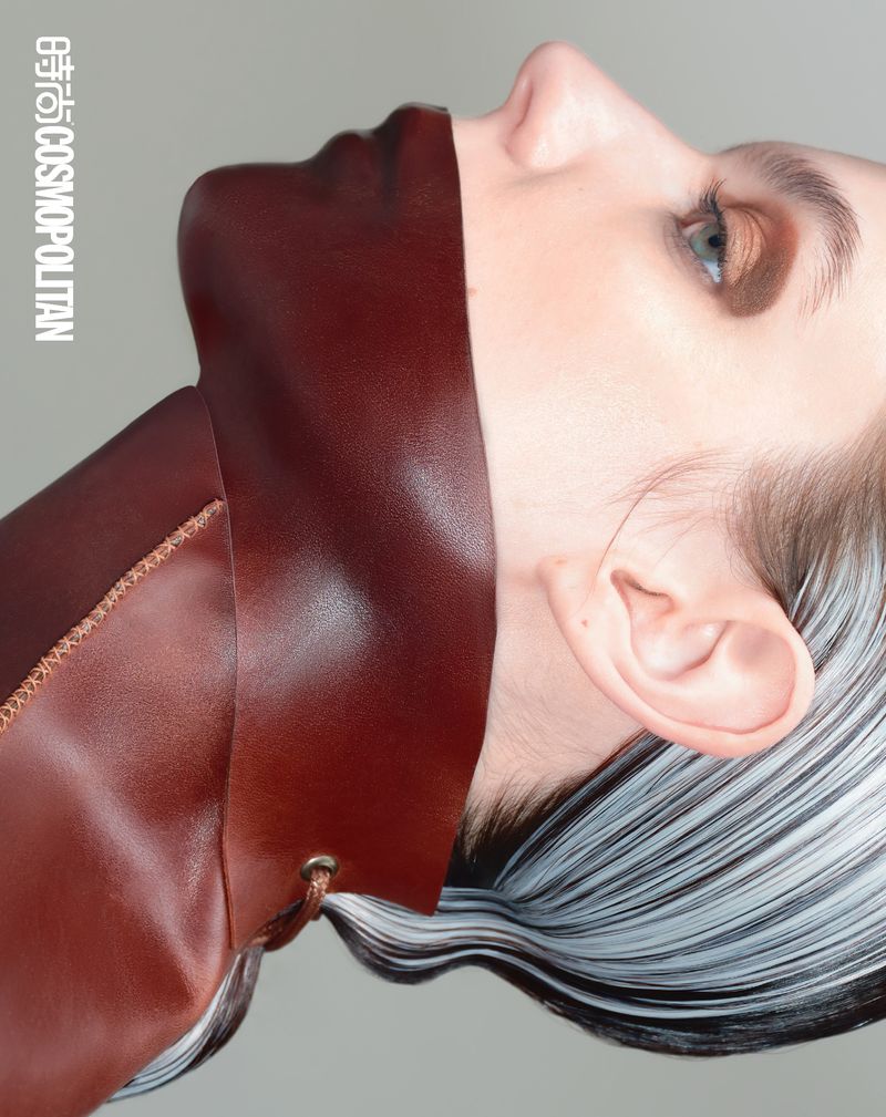 Fashion shot of a woman with brown leather covering her neck and lower face, showcasing unique style and makeup in a close-up.
