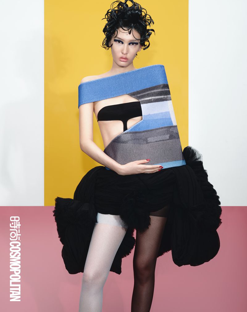 Fashion-forward image of a woman in a conceptual outfit against a vibrant two-tone backdrop, exuding editorial style and creative expression.