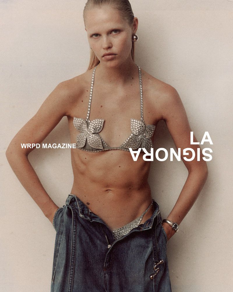 Model wearing a crystal-embellished floral top and denim jeans against a plain background for WRPD Magazine.