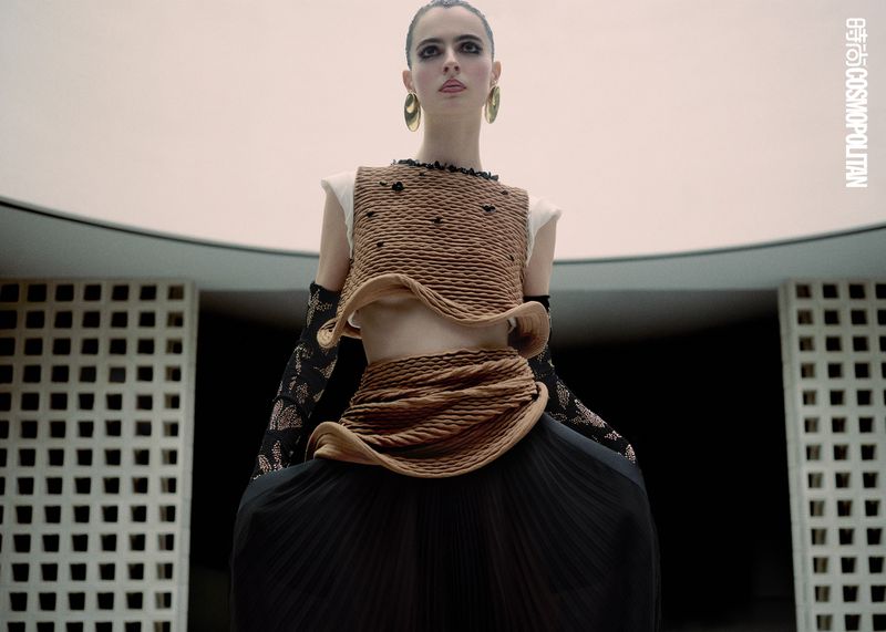 Fashion model wears a textured brown crop top and long black skirt in an editorial style portrait taken indoors.