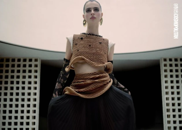 Fashion model wears a textured brown crop top and long black skirt in an editorial style portrait taken indoors.