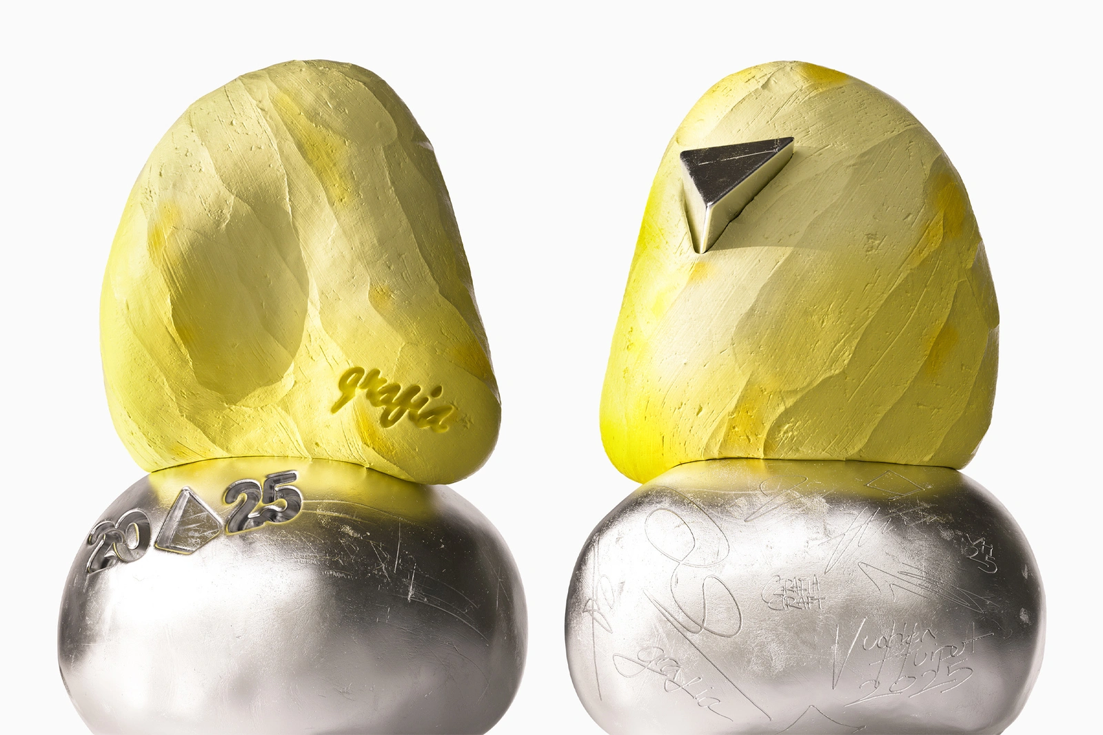 Two abstract sculptural objects with yellow textured upper portions and polished silver bases against a white background.