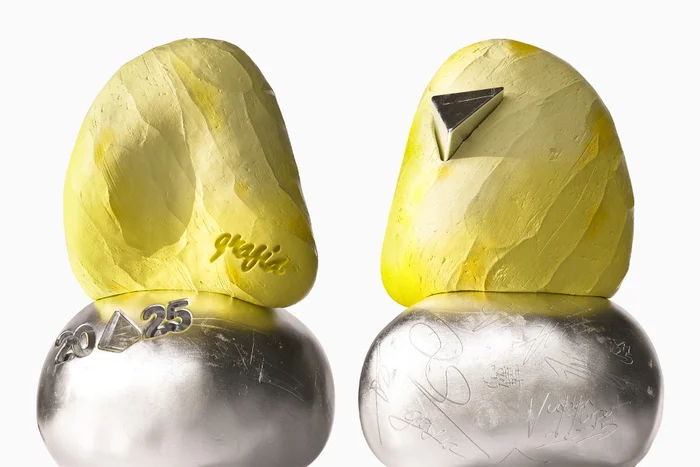 Two abstract sculptural objects with yellow textured upper portions and polished silver bases against a white background.