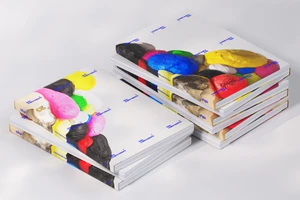 Two stacks of softcover books with colorful abstract clay relief covers resting on a clean white background