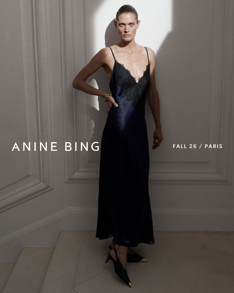 Model Malgosia Bela in a dark slip dress with lace trim standing against a panelled wall for Anine Bing Fall 2026.