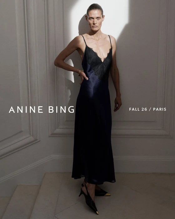 Model Malgosia Bela in a dark slip dress with lace trim standing against a panelled wall for Anine Bing Fall 2026.