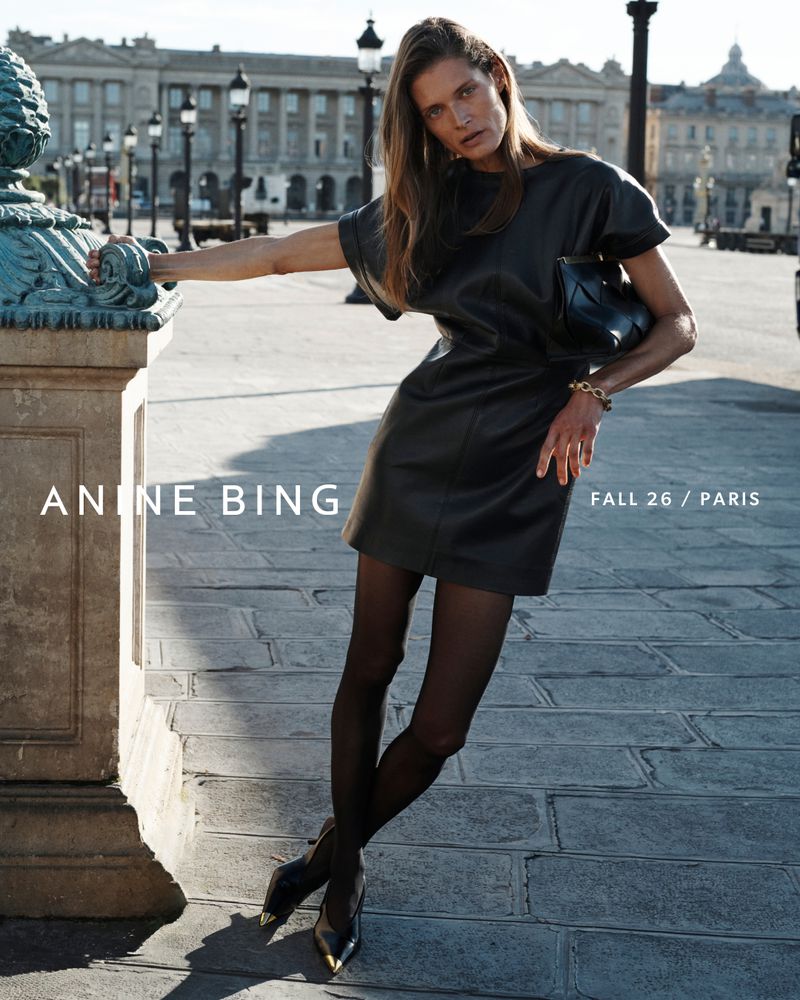 Model Malgosia Bela in a black leather dress posing outdoors in Paris for Anine Bing Fall 2026