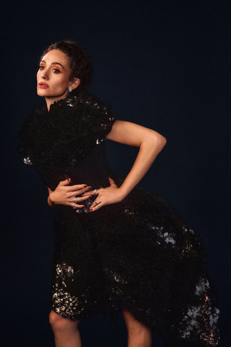 Emmy Rossum posing in a sculptural black textured dress against a dark background for InStyle U.S.