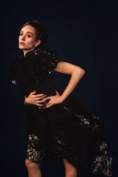 Emmy Rossum posing in a sculptural black textured dress against a dark background for InStyle U.S.