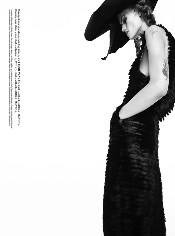 Model Lucia Richardson wearing a black textured dress and large wide-brim hat against a plain white background
