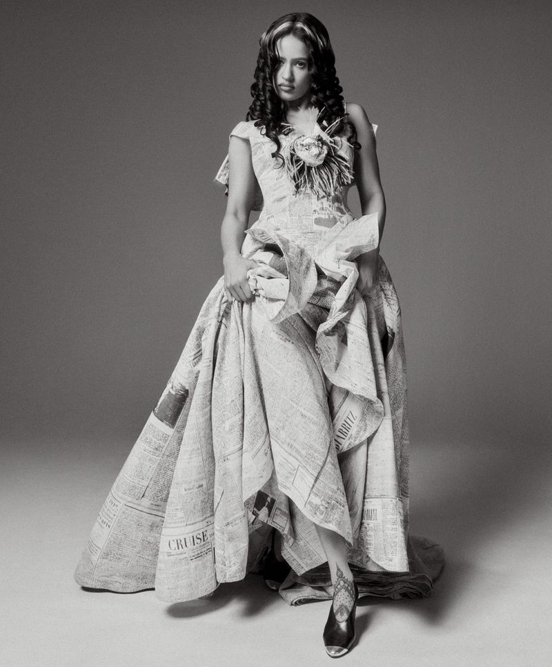 Rosalía wearing a structured gown made from printed newspaper in a monochromatic portrait for WSJ.