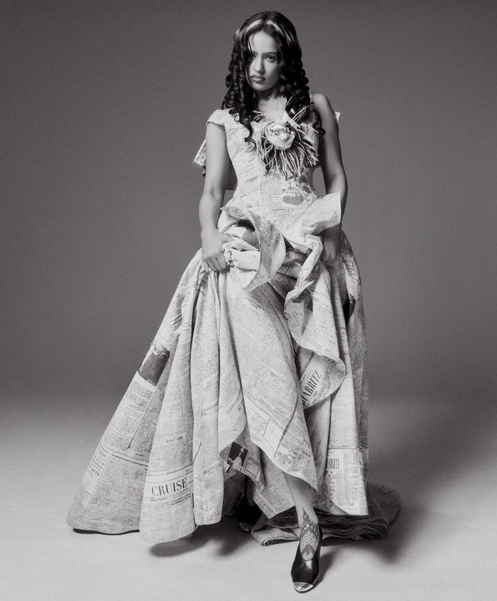 Rosalía wearing a structured gown made from printed newspaper in a monochromatic portrait for WSJ.
