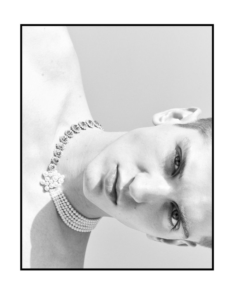Close-up portrait of a male model wearing a pearl choker necklace against a light background for Esquire China