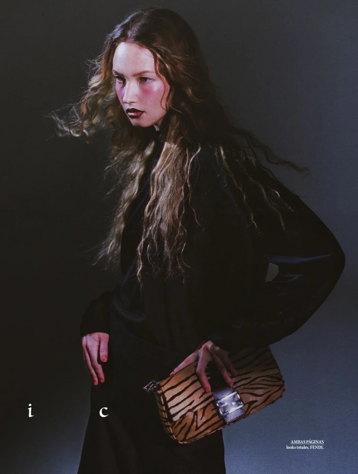 Model with long curly hair in black top holding a tiger-print handbag for Elle Mexico shot by Jesús Soto Fuentes