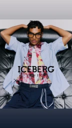 Model wearing dark glasses and blue shirt leaning back on a black leather sofa for Iceberg Summer 2026 Collection