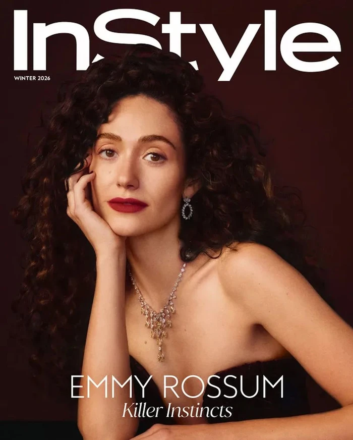 Emmy Rossum with dark curly hair wearing a statement necklace and dark strapless dress against a deep background for InStyle U.S.