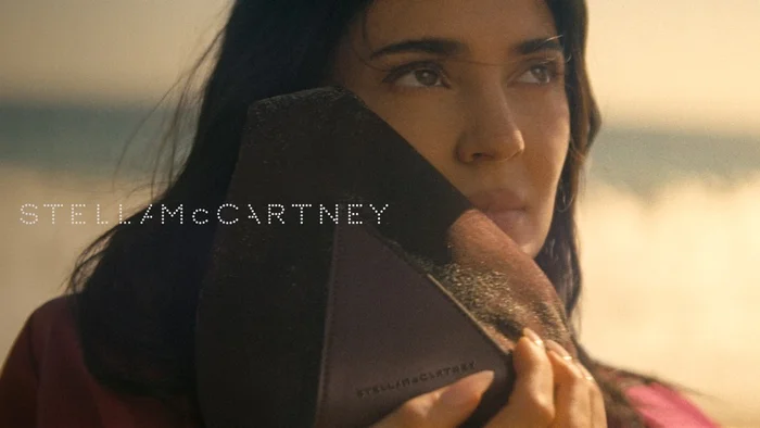 Kylie Jenner holding a handbag against a sandy beach background for Stella McCartney Wild Horses project