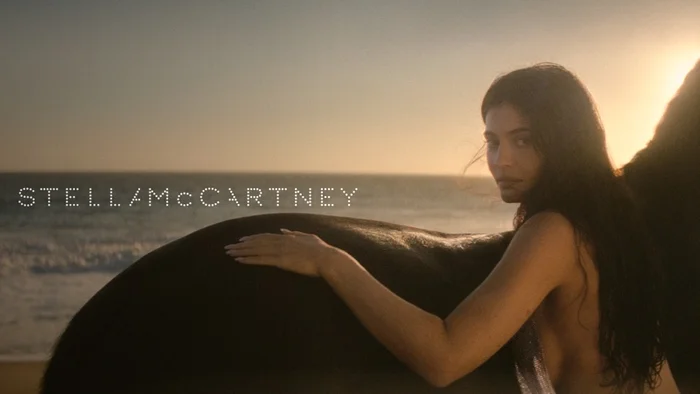 Kylie Jenner resting her hand on a horse at sunset on a sandy beach for Stella McCartney