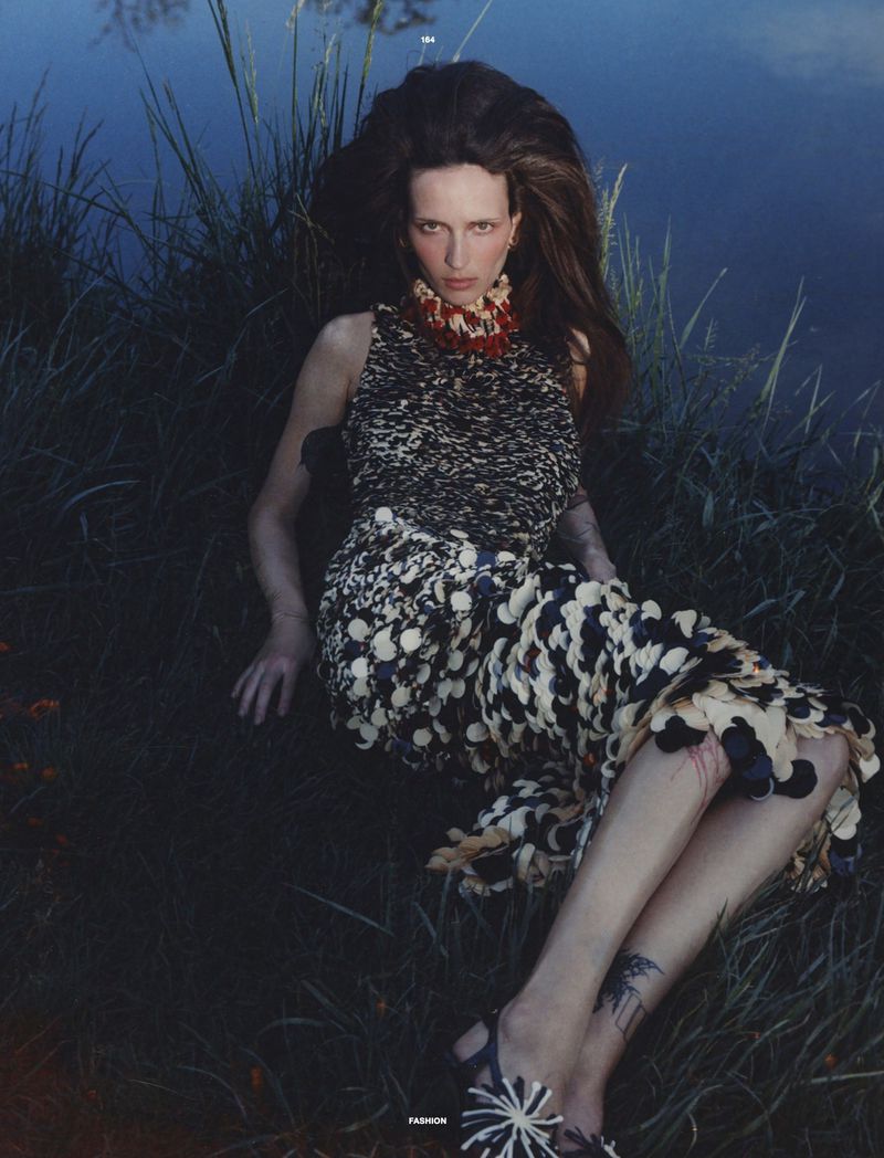 Model Waleska Gorczevski seated amongst tall grass by water for Numero Netherlands editorial photography.
