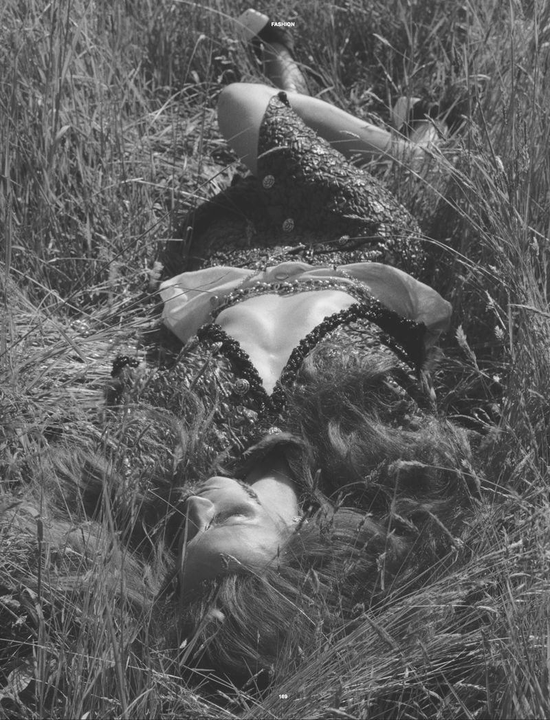 Model Waleska Gorczevski lying among tall grass in a high-contrast black and white fashion editorial photograph for Numero Netherlands.
