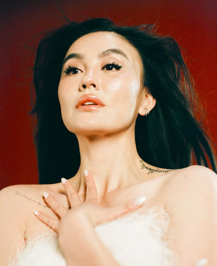 Portrait of Agnez Mo with dark flowing hair and light makeup against a deep red background for Schön Magazine.