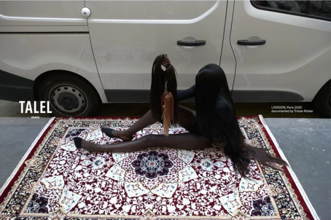 Woman in full body suit poses on patterned rug with hair extensions and van in the background, creating a surreal fashion image.