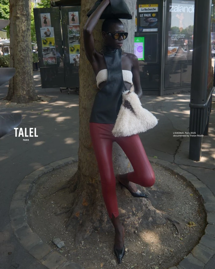 Model leaning against a tree on a street wearing red leather pants, white fuzzy top, and black sunglasses for Talel Paris SS26