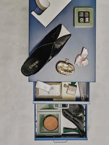Top-down view of a blue metal cabinet with drawers, displaying Chanel shoes, a metallic purse, and stationery for L'Officiel Italia.