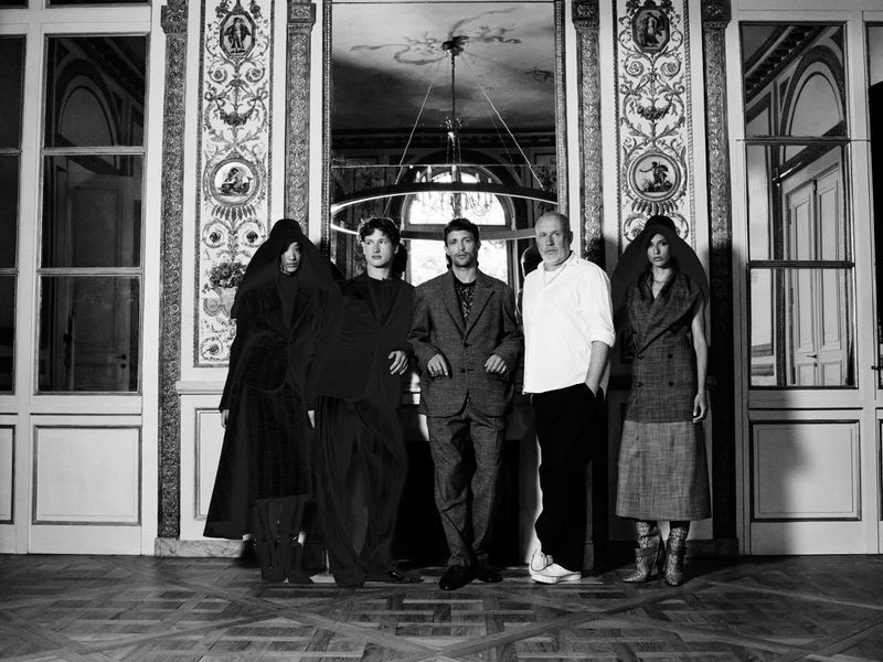 Five people posed in a grand room with ornate walls and parquet floors for an editorial project by Paolo Musa.