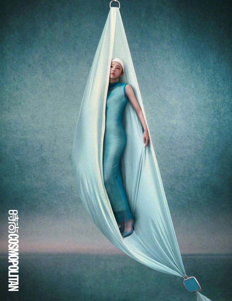 Chen Duling suspended inside a flowing light blue aerial silk fabric against a textured moody background for Cosmopolitan China.