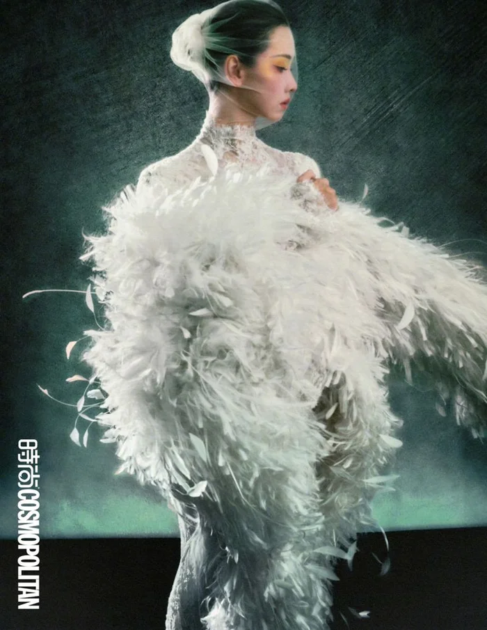 Chen Duling in a white feathered gown and lace turtleneck with a veil against a dark textured background for Cosmopolitan China