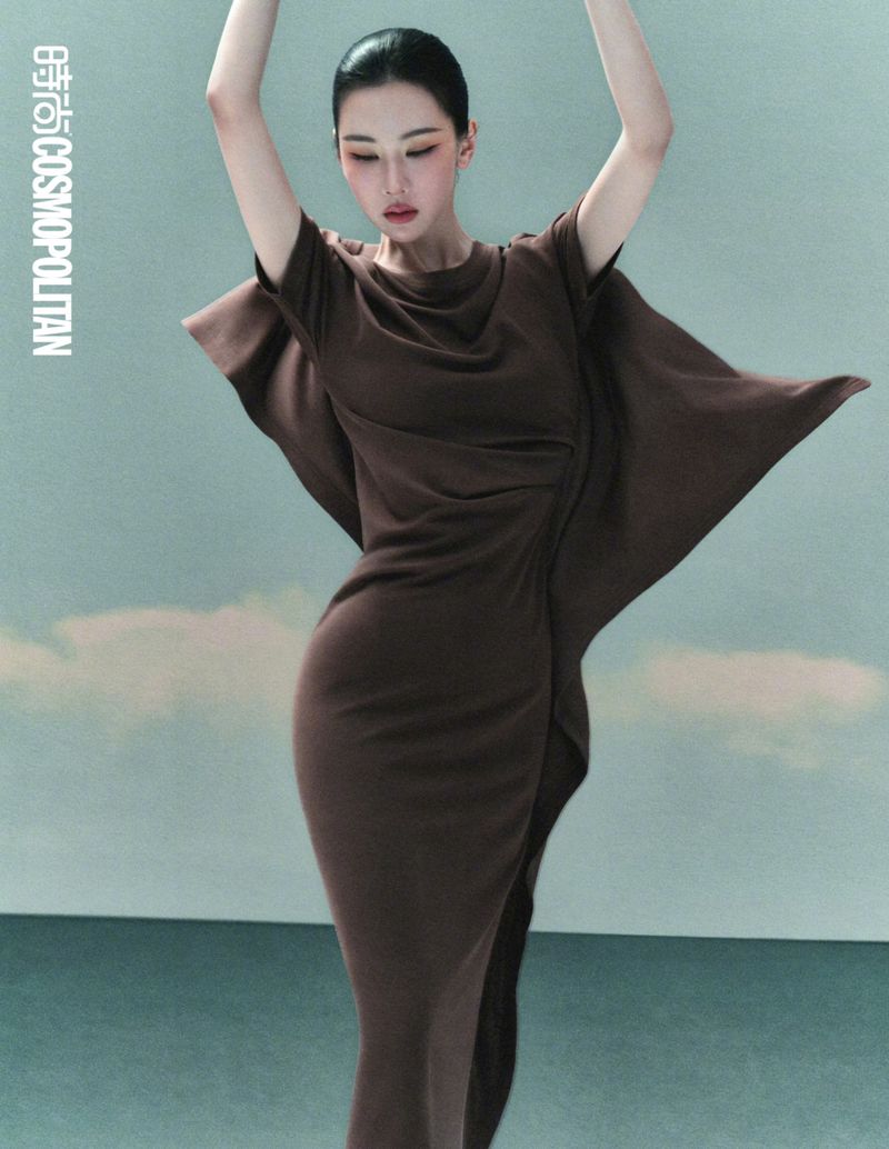 Chen Duling in a fitted brown dress with draped sleeves posing against a studio backdrop for Cosmopolitan China by Songze Tu.