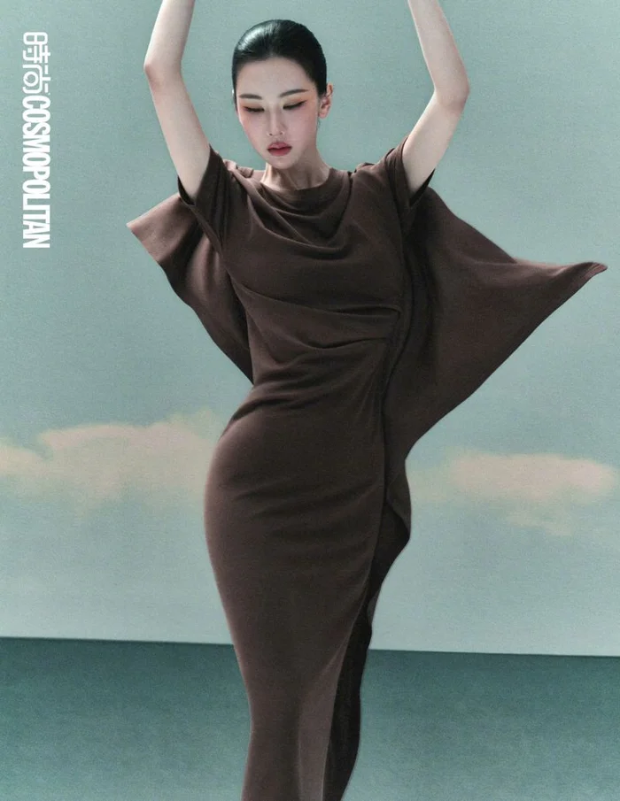 Chen Duling in a fitted brown dress with draped sleeves posing against a studio backdrop for Cosmopolitan China by Songze Tu.