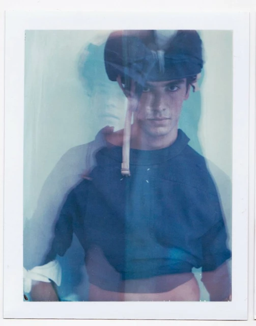Polaroid portrait of a young man with short dark hair wearing a navy shirt with multiple-exposure blurring effects.