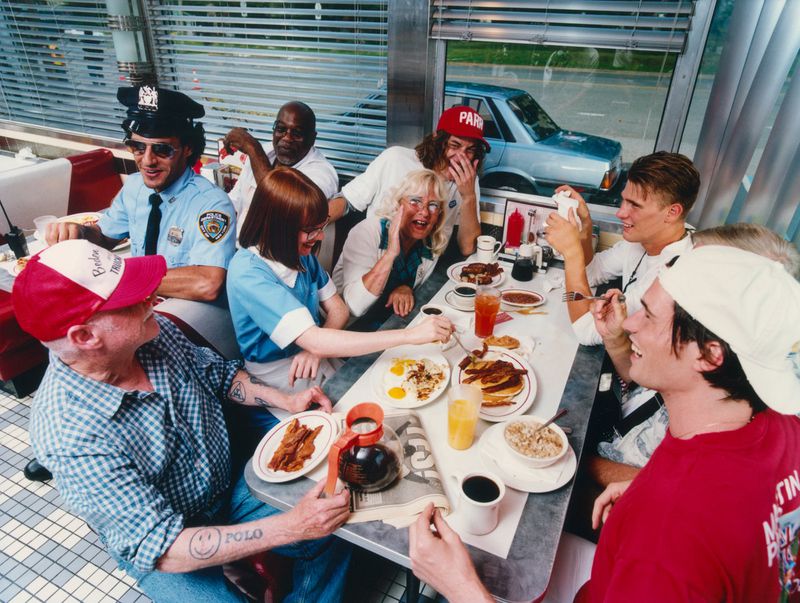 Group of diverse people seated around a diner table eating breakfast, captured by Samuel Bradley for Zara.