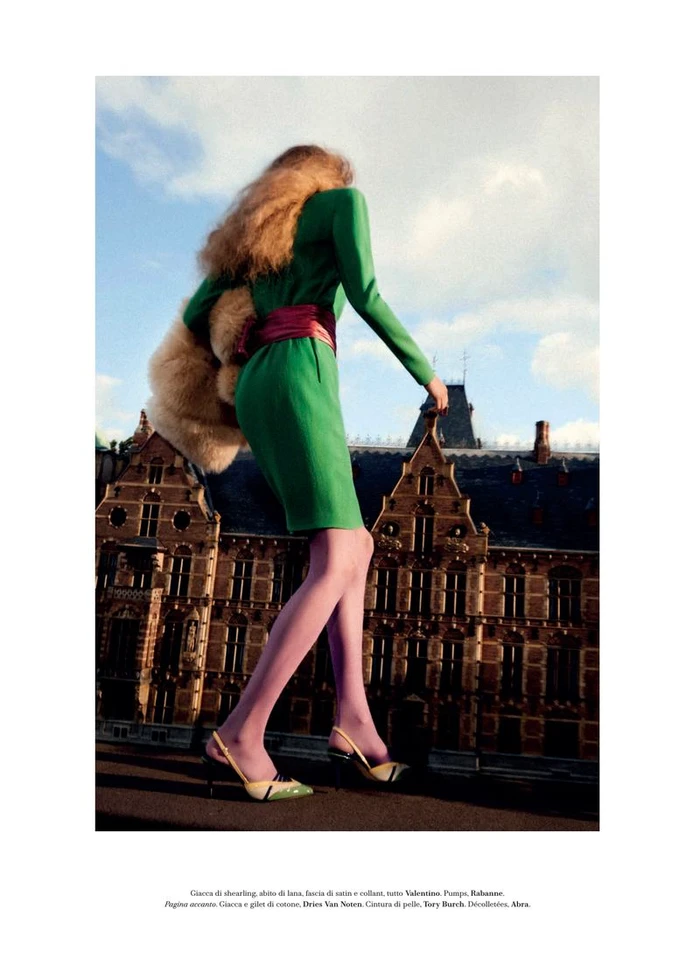 Model Frauke Nijs in a green dress and pink tights walking against an architectural backdrop by Carlijn Jacobs