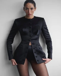 Model Cora Corré wearing a tailored black buttoned jacket against a pale grey studio background for Violet Book project Cora