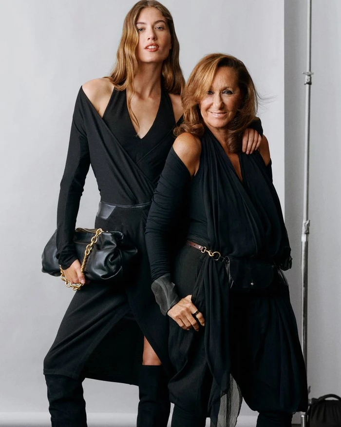 Two women wearing black dresses standing against a neutral studio backdrop, photographed by Scott Trindle for Macy's.