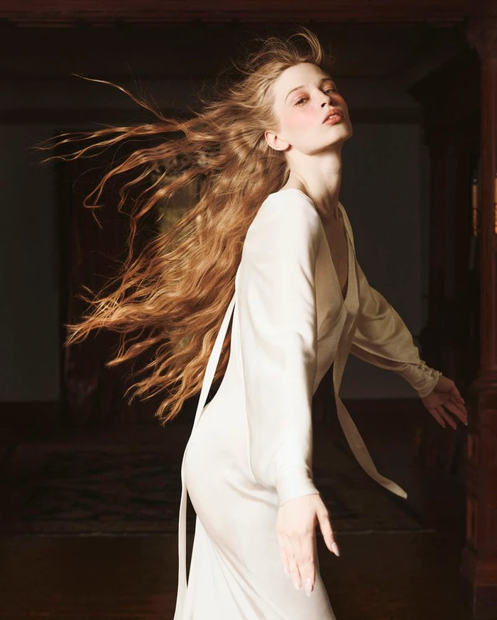 Model in a cream silk dress with long flowing brown hair in a dark interior for Vogue Czechoslovakia