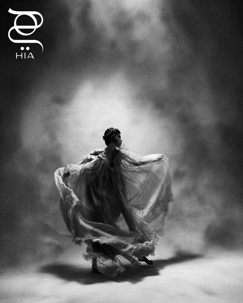 Dramatic black and white image of an adult female figure in flowing gown, dynamically posed with visible motion blur.