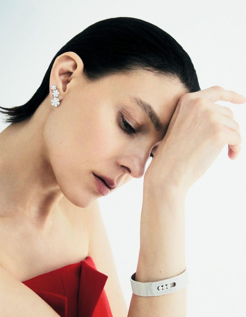 Close-up portrait of a woman with dark hair wearing a red dress and silver jewelry against a white background in a photo studio.